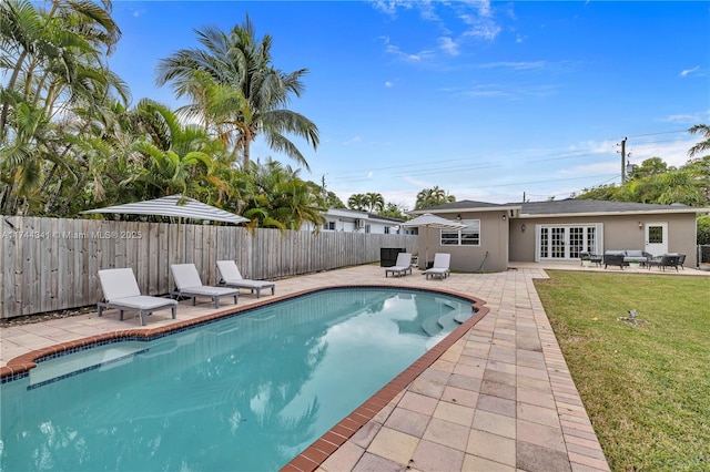 view of pool with french doors, a yard, and a patio