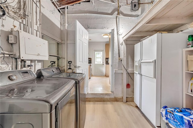 laundry room with washing machine and clothes dryer and light hardwood / wood-style floors