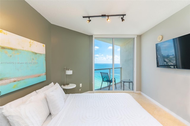 bedroom with access to exterior, a wall of windows, and rail lighting