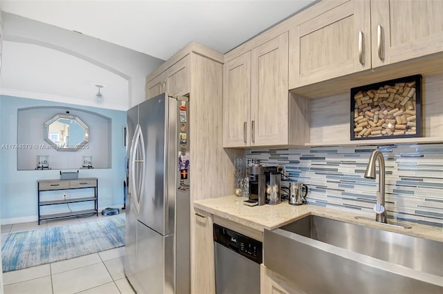 kitchen featuring stainless steel appliances, sink, light tile patterned floors, and light brown cabinetry