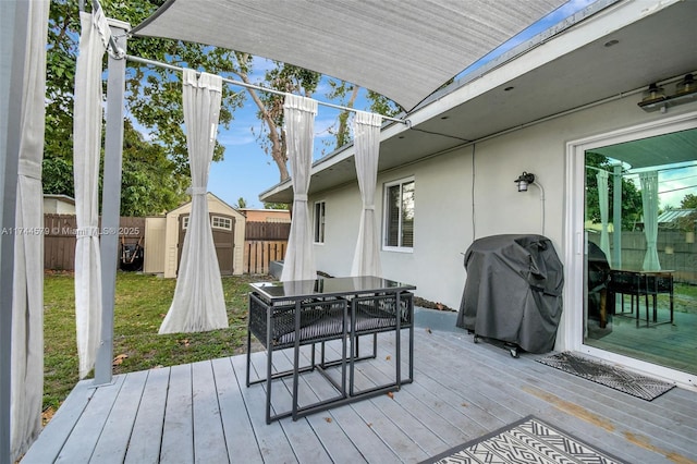 wooden terrace with a storage shed and a grill