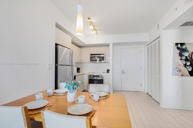 dining area featuring rail lighting and light hardwood / wood-style flooring