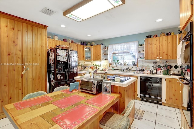 kitchen featuring light tile patterned floors, decorative backsplash, black appliances, and a center island