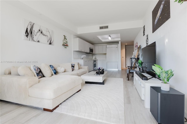 living room featuring a tray ceiling and sink