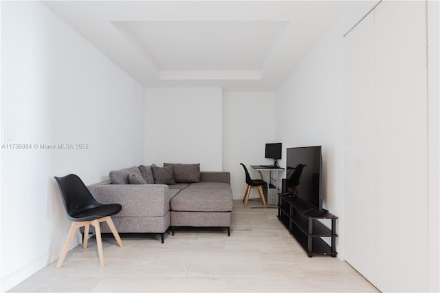 living room featuring light hardwood / wood-style floors and a raised ceiling