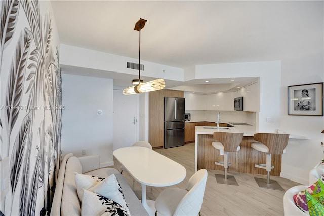 kitchen featuring sink, hanging light fixtures, kitchen peninsula, stainless steel appliances, and white cabinets