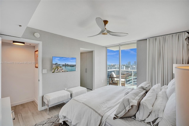 bedroom with access to exterior, light hardwood / wood-style flooring, expansive windows, and ceiling fan