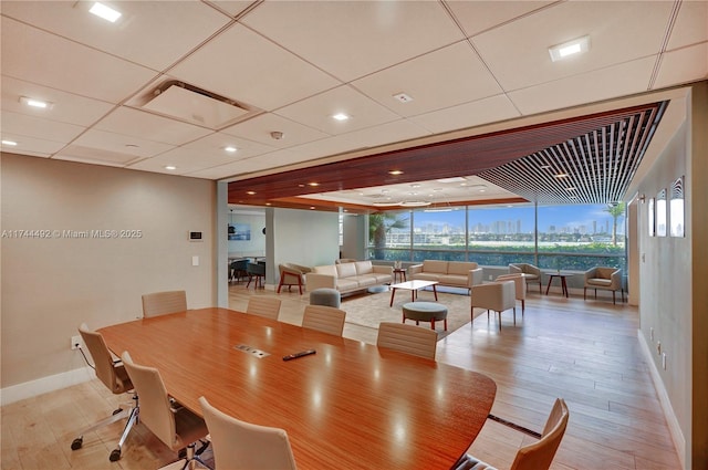 dining space with a paneled ceiling, floor to ceiling windows, and light wood-type flooring