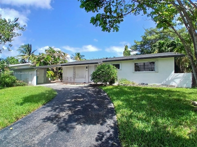 ranch-style home with a carport, a front yard, and driveway