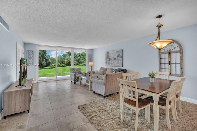 dining area featuring a wall of windows, a textured ceiling, and light tile patterned floors