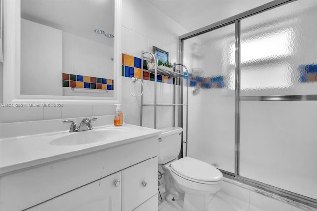 bathroom featuring vanity, tile walls, and toilet