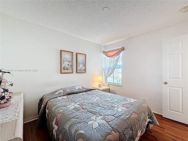 bedroom featuring a textured ceiling, baseboards, and dark wood-style flooring