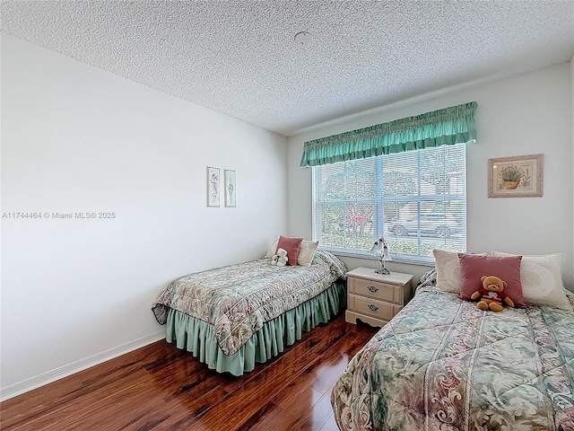 bedroom featuring dark wood-style floors, a textured ceiling, and baseboards