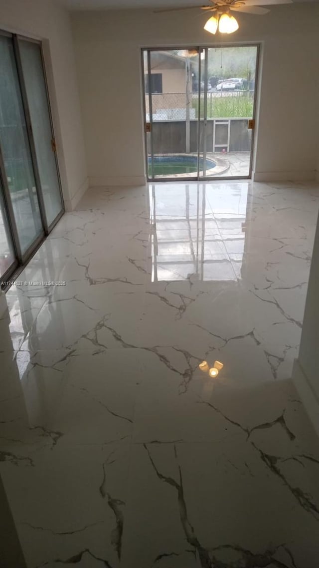 spare room featuring marble finish floor and baseboards