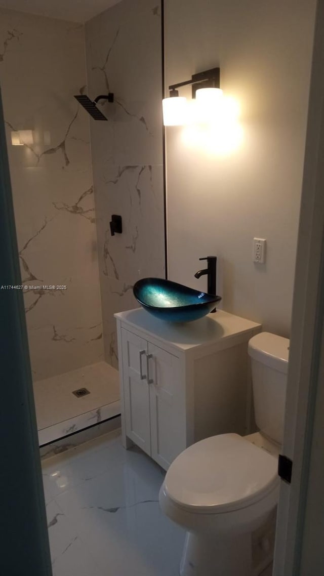 bathroom with marble finish floor, toilet, vanity, and a marble finish shower