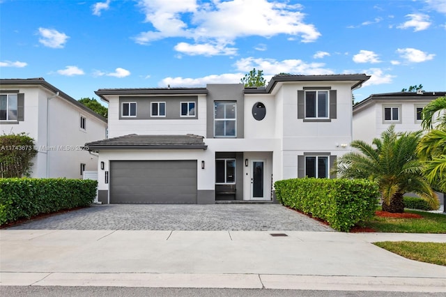 view of front of home with a garage, a tile roof, decorative driveway, and stucco siding