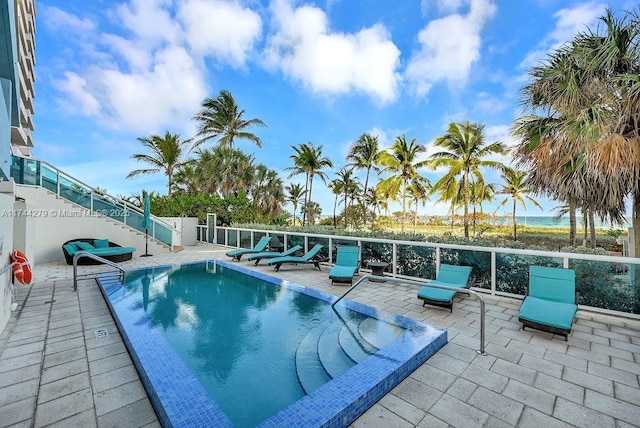 view of pool with a water view and a patio area