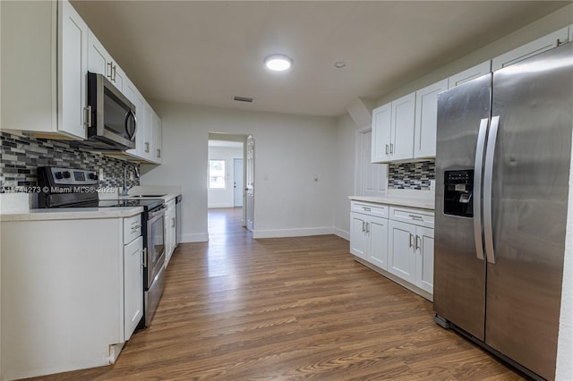 kitchen featuring tasteful backsplash, white cabinetry, appliances with stainless steel finishes, and dark hardwood / wood-style floors