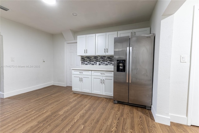 kitchen featuring white cabinetry, backsplash, hardwood / wood-style flooring, and stainless steel fridge