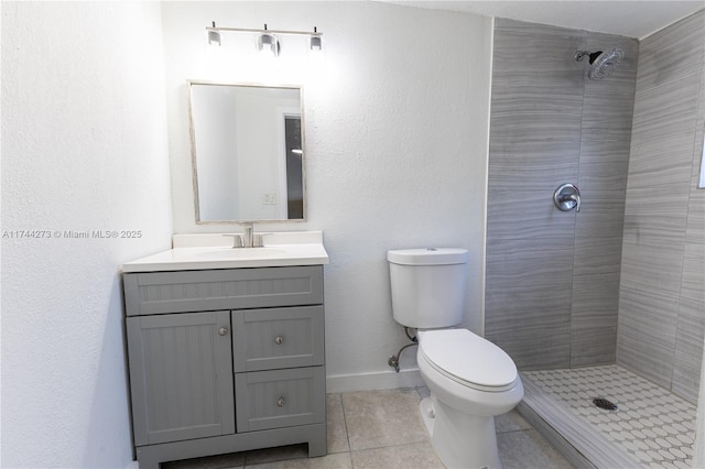 bathroom with tile patterned flooring, vanity, tiled shower, and toilet