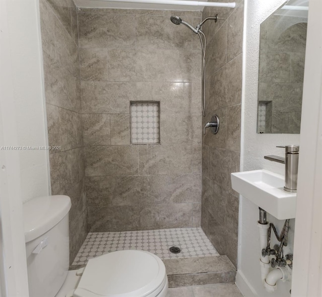 bathroom with toilet, sink, and a tile shower