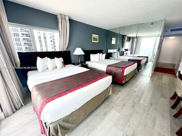 bedroom featuring a textured ceiling, multiple windows, and light wood-type flooring