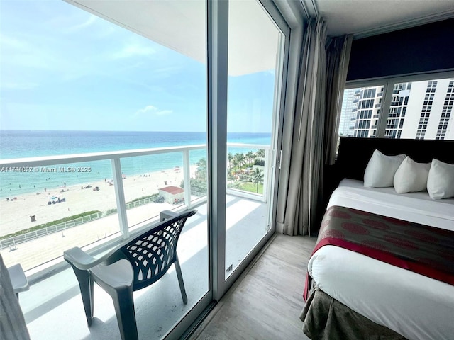 bedroom featuring a water view, a beach view, and light hardwood / wood-style flooring