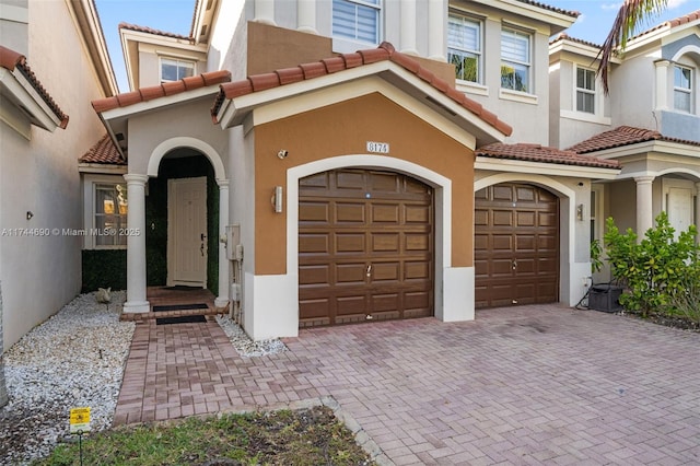 view of front facade with stucco siding, a garage, driveway, and a tiled roof