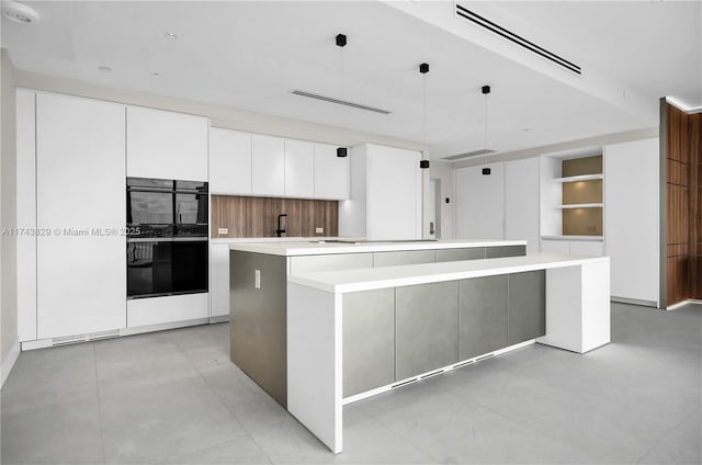 kitchen with a large island, white cabinetry, light countertops, and dobule oven black