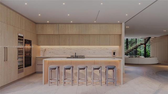 kitchen featuring a kitchen breakfast bar, a kitchen island with sink, and backsplash