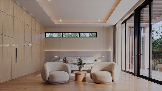 sitting room featuring light hardwood / wood-style floors, a raised ceiling, and a high ceiling