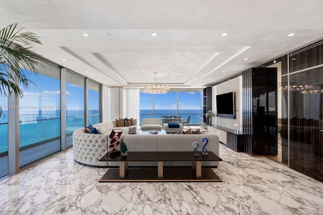 living room with expansive windows, a notable chandelier, and a tray ceiling