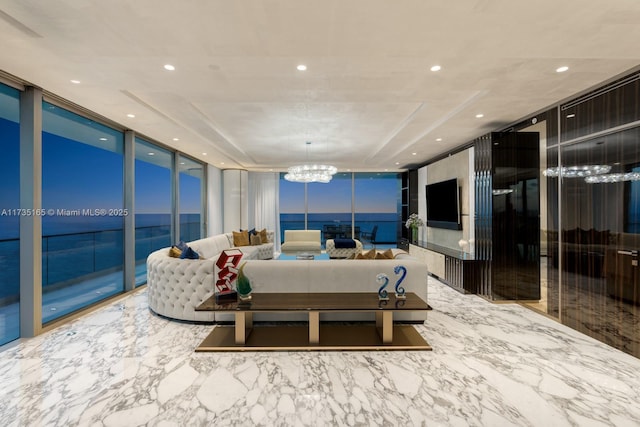 living room with an inviting chandelier, a wall of windows, and a raised ceiling