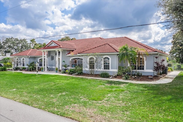 mediterranean / spanish-style house featuring stucco siding, a front lawn, and a tiled roof