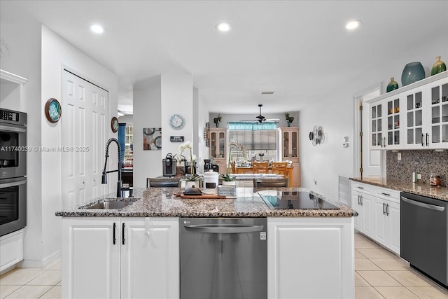 kitchen featuring a center island with sink, glass insert cabinets, white cabinets, a sink, and black appliances