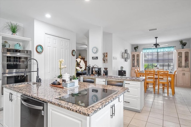 kitchen with visible vents, white cabinets, a ceiling fan, appliances with stainless steel finishes, and a center island