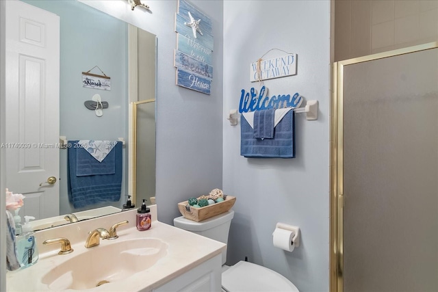 bathroom with toilet, vanity, and a shower with shower door