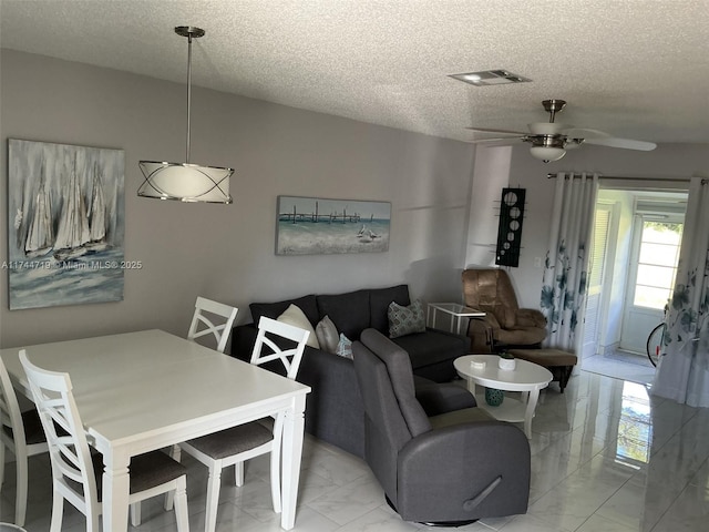 living room with a textured ceiling and ceiling fan