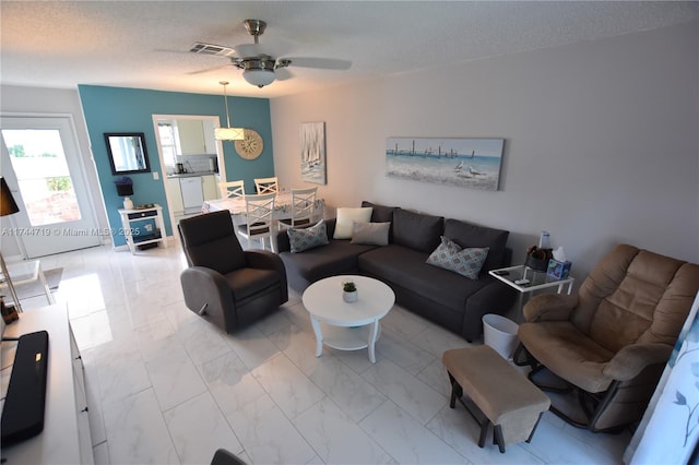 living room featuring ceiling fan and a textured ceiling