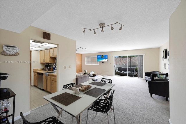 dining room with rail lighting, sink, light carpet, and a textured ceiling