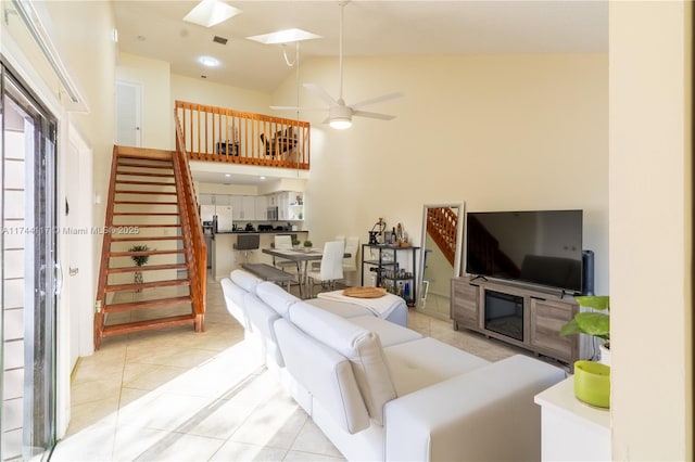 living room featuring ceiling fan, a skylight, high vaulted ceiling, and light tile patterned floors