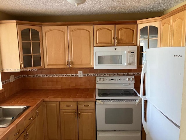 kitchen with tasteful backsplash, sink, tile counters, and white appliances