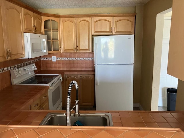 kitchen featuring tasteful backsplash, sink, white appliances, and tile countertops