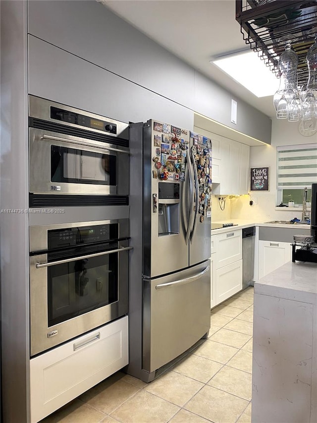 kitchen featuring white cabinetry, sink, stainless steel appliances, and light tile patterned flooring