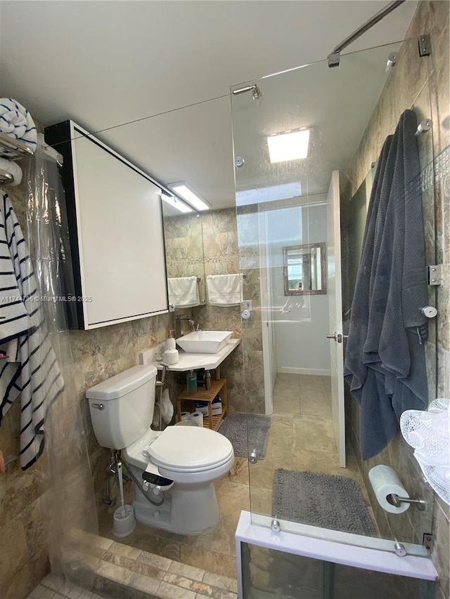 bathroom featuring toilet, curtained shower, sink, and tile walls