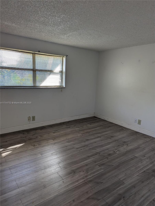 unfurnished room featuring a textured ceiling, dark wood finished floors, and baseboards