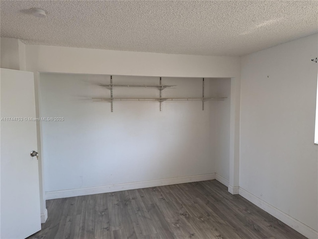 interior space with a closet, a textured ceiling, baseboards, and wood finished floors