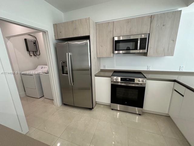 kitchen with stainless steel appliances, light brown cabinetry, and independent washer and dryer