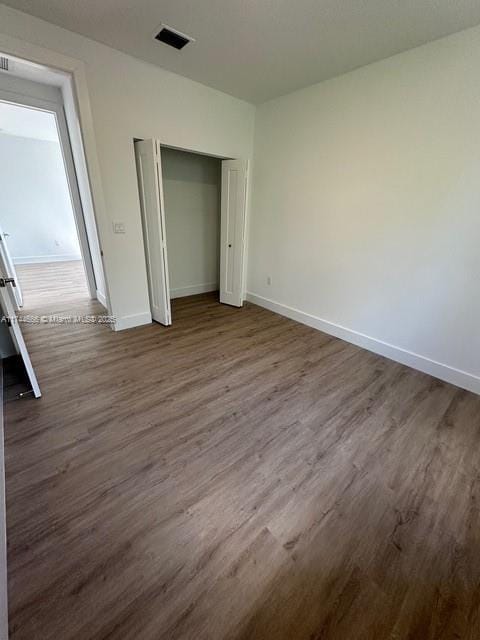 unfurnished bedroom with dark wood-type flooring and a closet