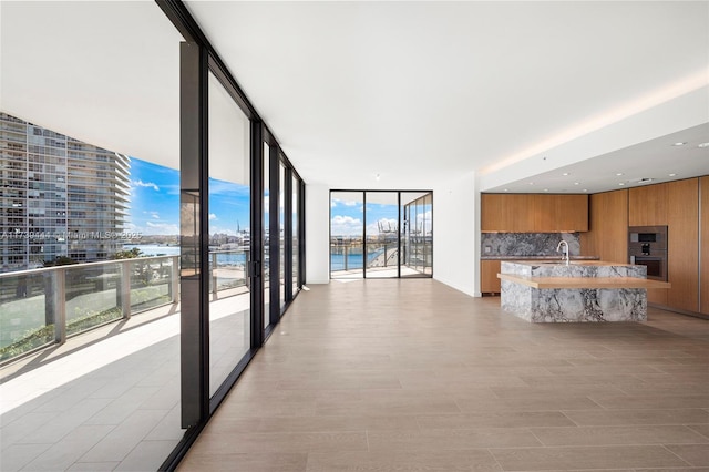 interior space with sink, light hardwood / wood-style floors, expansive windows, and a water view